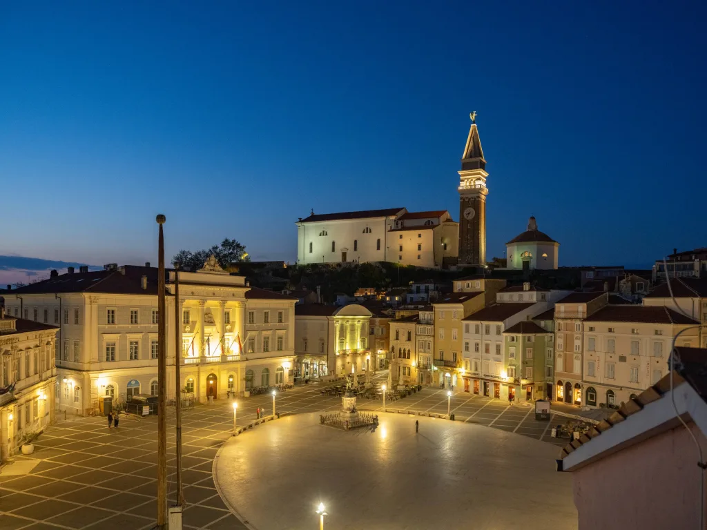 Trg Tartinija v Piranu izven sezone, osvetljen in prazen zvečer